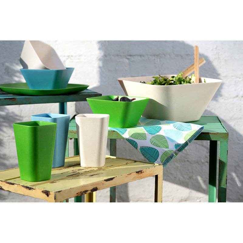 Outdoor dining accessories with colourful cups, bowls and serving dishes arranged on garden tables