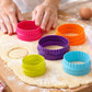Set of 5 round fluted cookie cutters in bright colors cutting circles from rolled dough