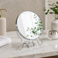 Small silver shaving mirror with round frame on bathroom counter