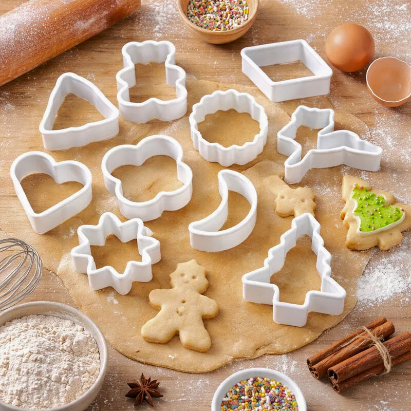 White plastic cookie cutter set in holiday shapes on rolled dough with a gingerbread cookie, flour and cinnamon sticks