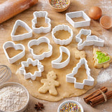 White plastic cookie cutter set in holiday shapes on rolled dough with a gingerbread cookie, flour and cinnamon sticks
